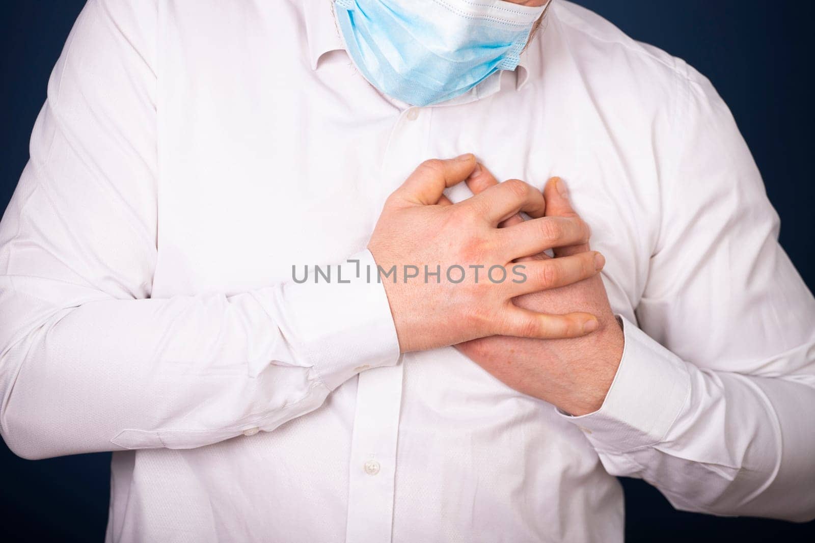 Man wearing medical face mask with chest pain - heart attack, shortness of breath during work in office.