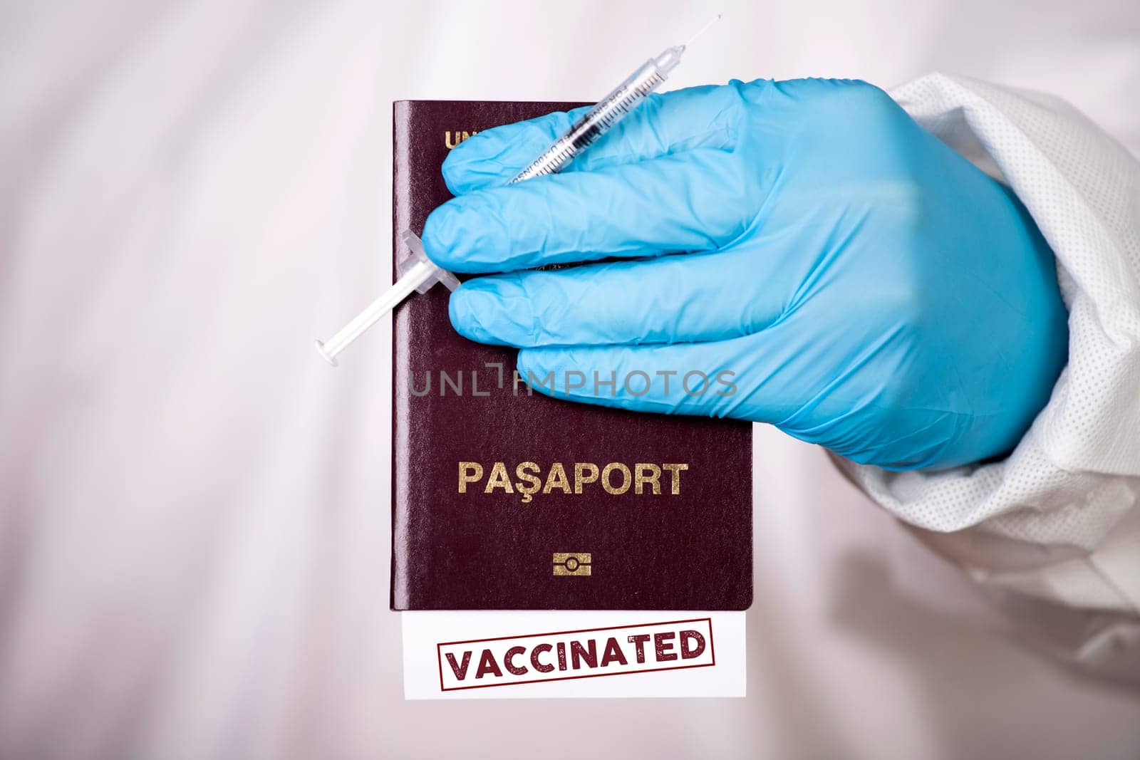 Doctor holding passport with VACCINATED sign and vaccine. Immunity passport, risk-free certificate concept.