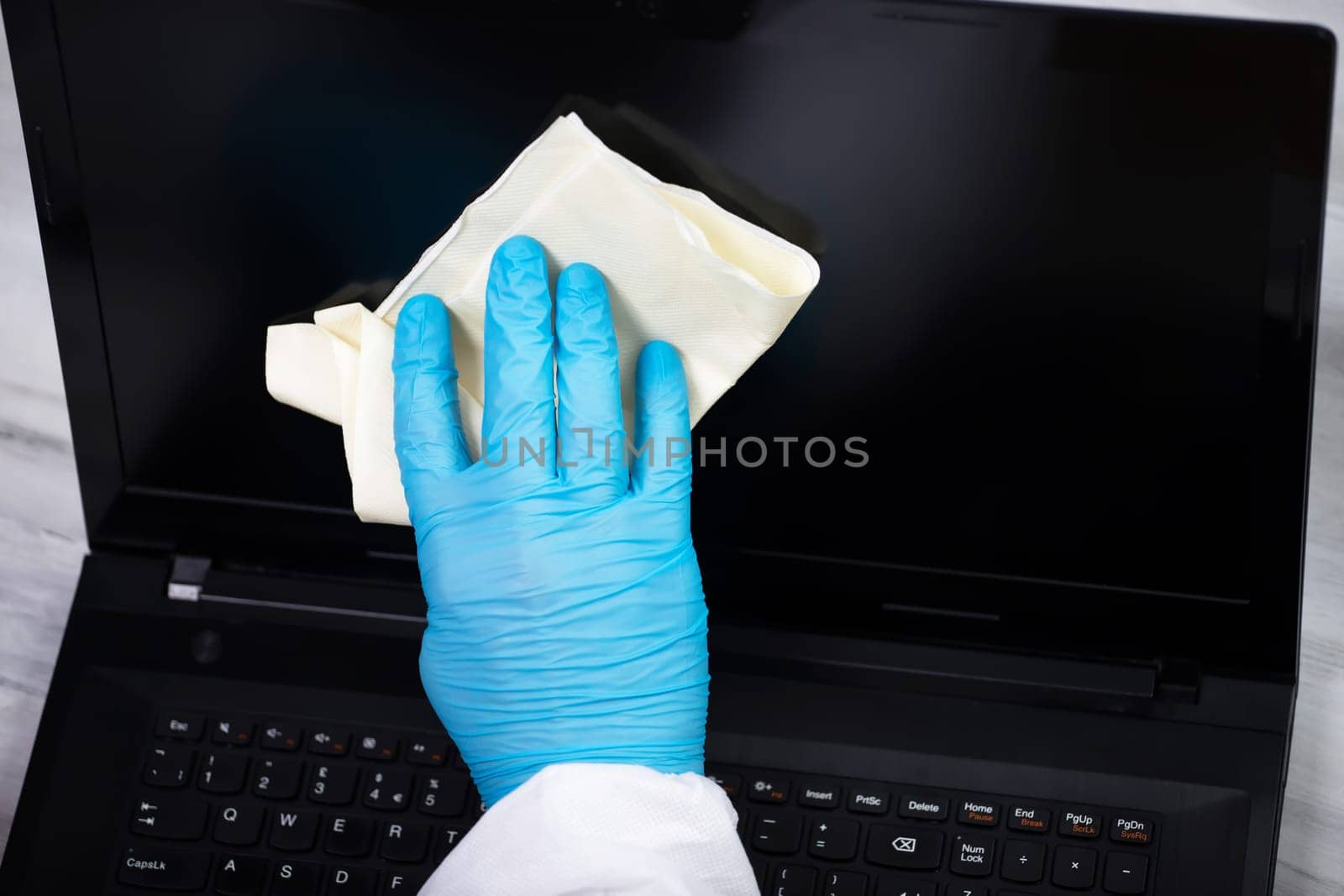 Office sanitizing wiping laptop with disinfectant. Coronavirus COVID-19 sanitize cleaning, disinfection of work desk.