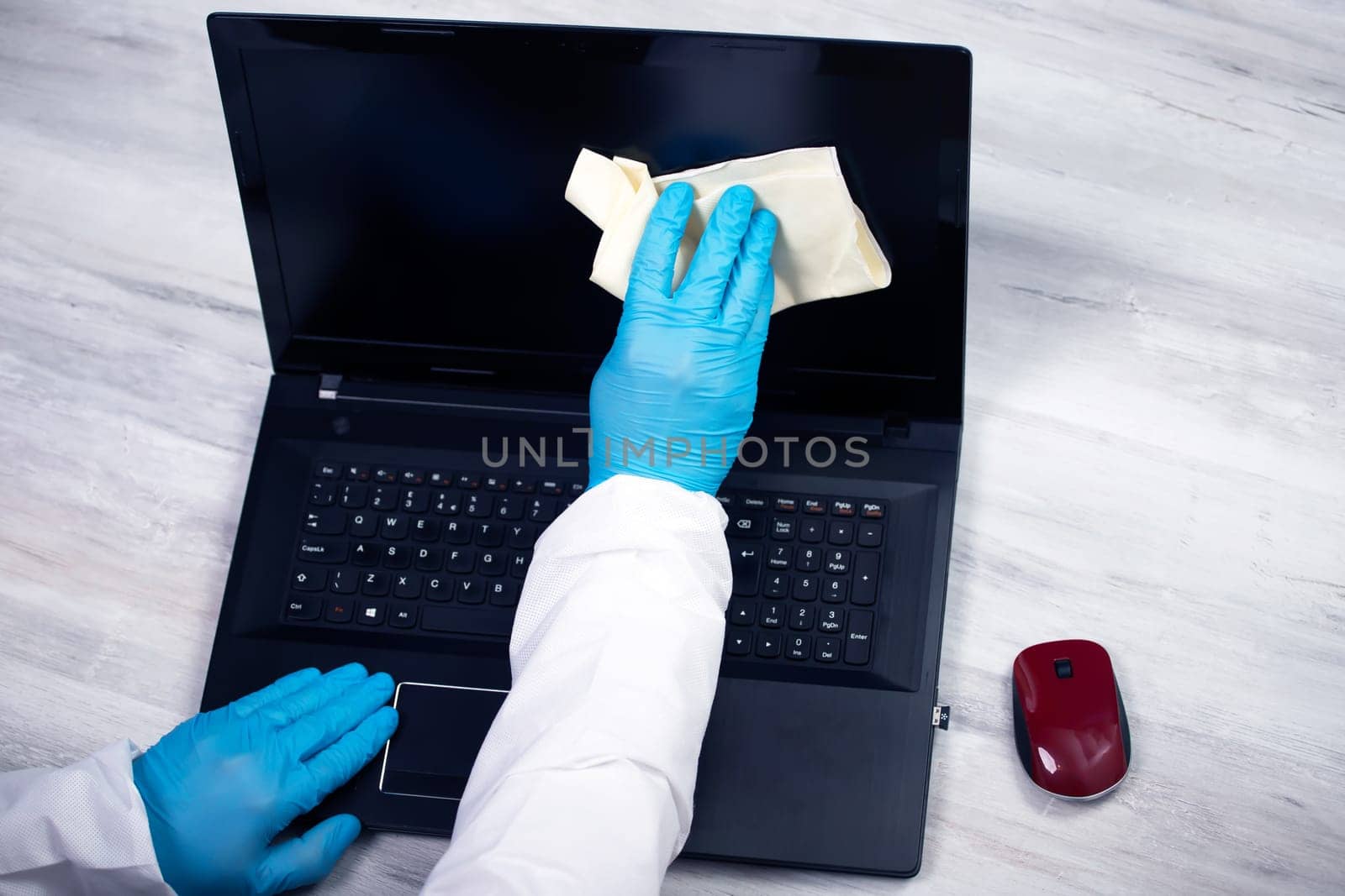 Office sanitizing wiping laptop with disinfectant. Coronavirus COVID-19 sanitize cleaning, disinfection of work desk.