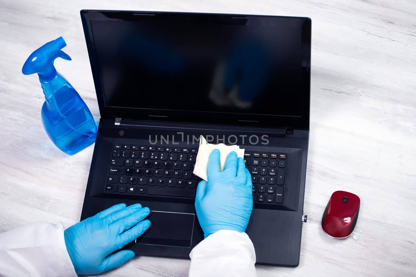 Office sanitizing wiping laptop with disinfectant. Coronavirus COVID-19 sanitize cleaning, disinfection of work desk.