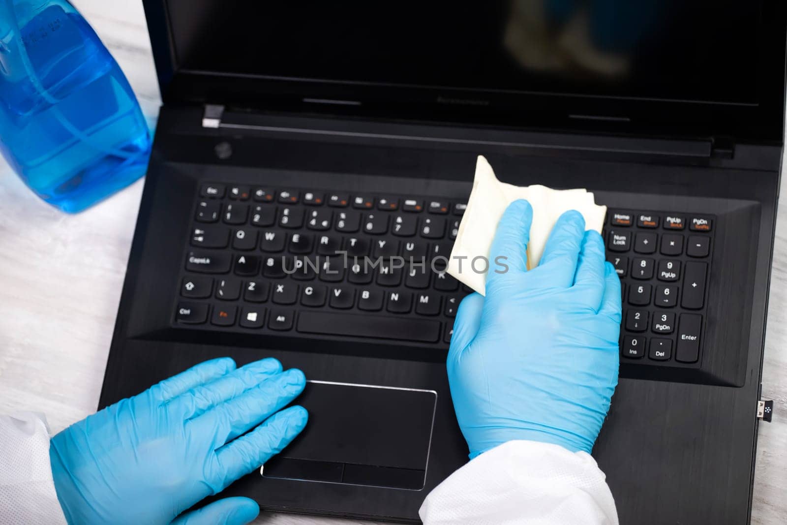Office sanitizing wiping laptop with disinfectant. Coronavirus COVID-19 sanitize cleaning, disinfection of work desk.