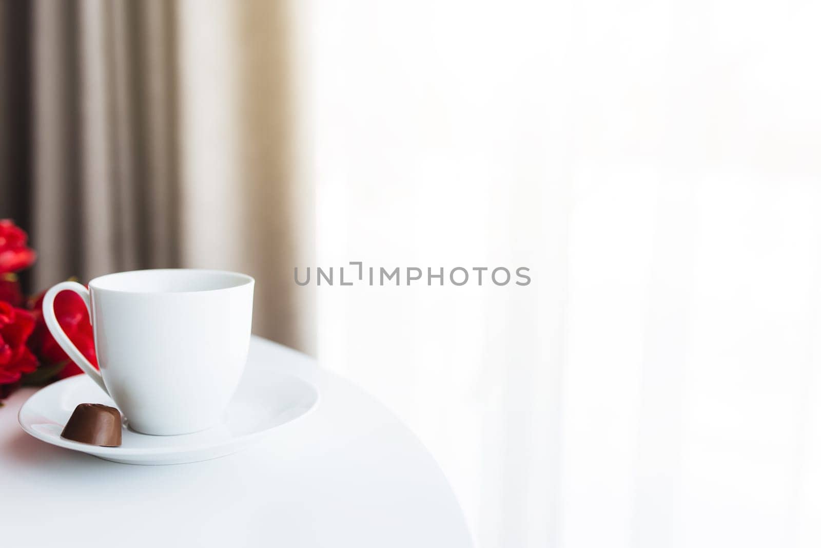 Red tulips bouquete on table, white coffee cup. Concept for greeting card for mothers day, international womans day or valentines day concept, birthday greeting concept, dark chocolate candy