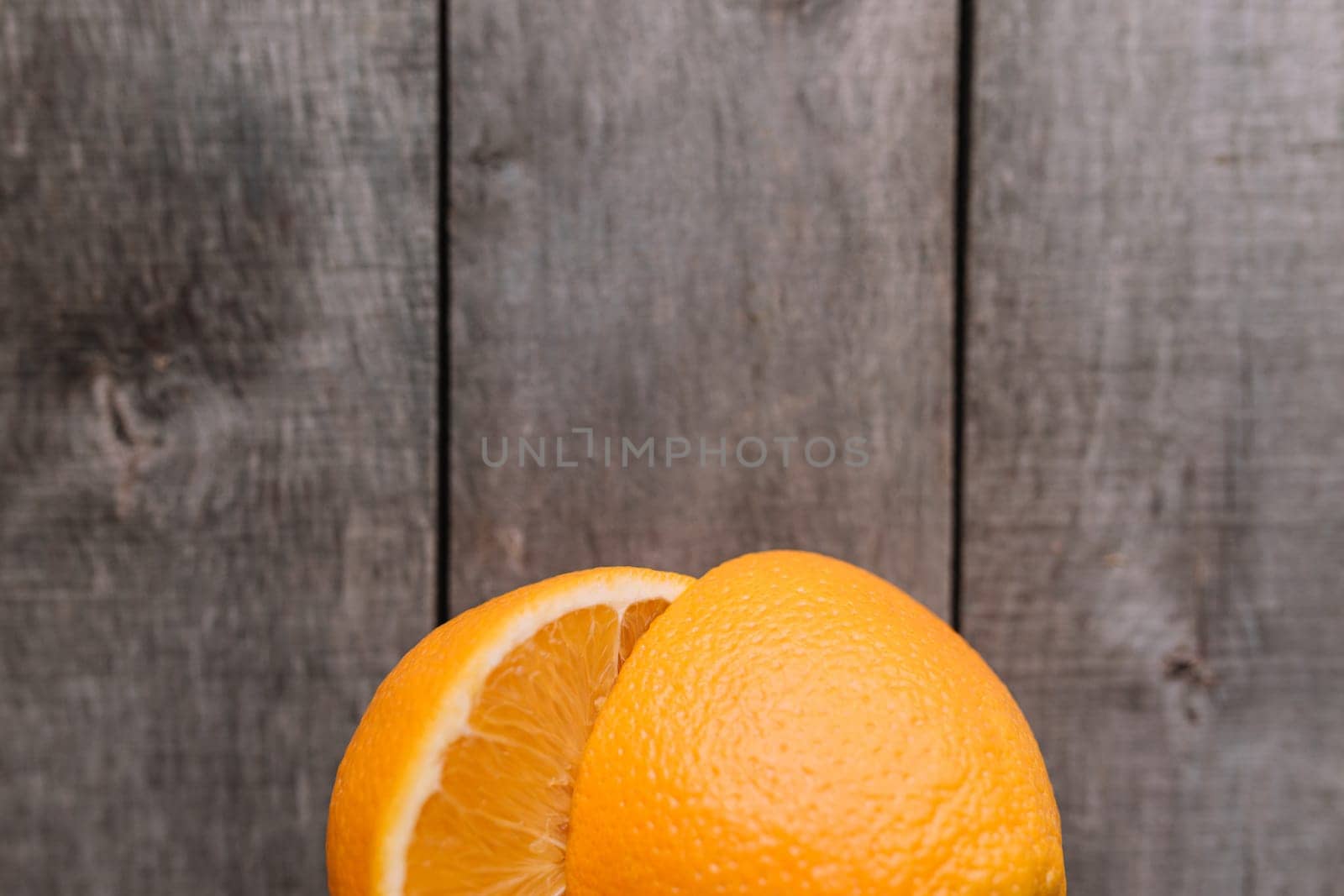 Flat lay with fresh ripe sliced halves of orange fruit on gray wooden background. Orange pulp and green leaves. Tropic food concept. Healthy eating concept. High quality photo