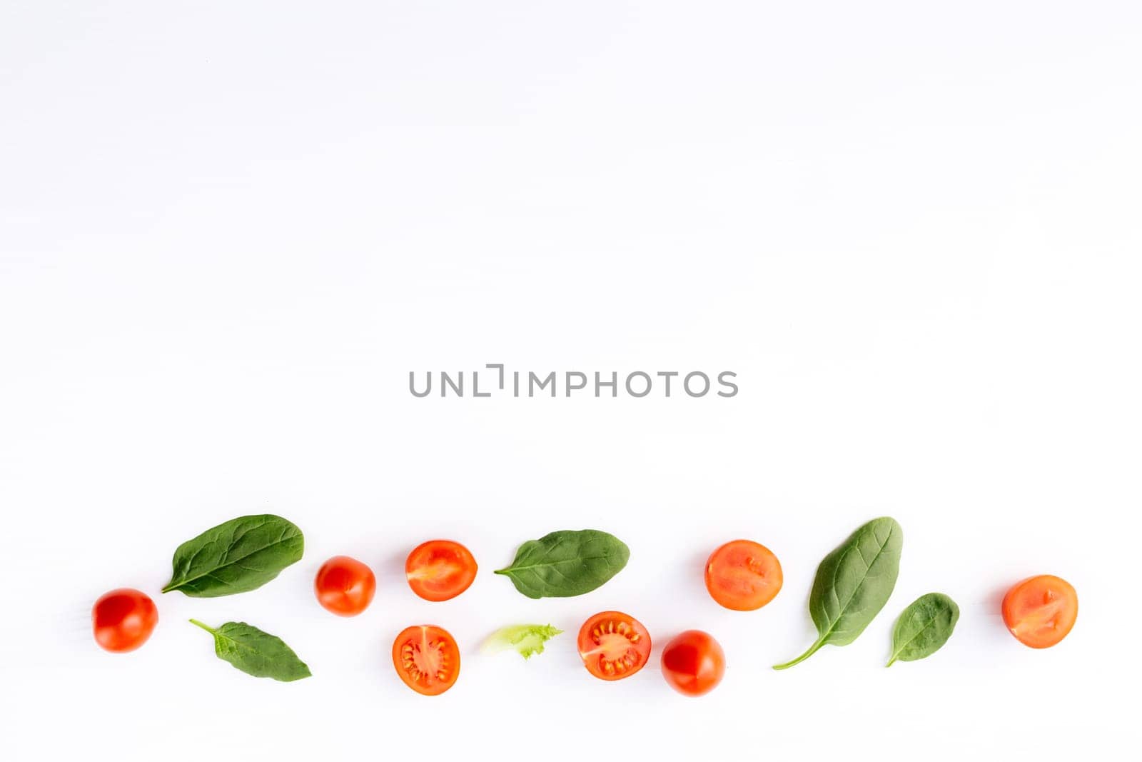Flat lay with red cherry tomatoes and green spinach leaves on a white background. Healthy eating concept. High quality photo