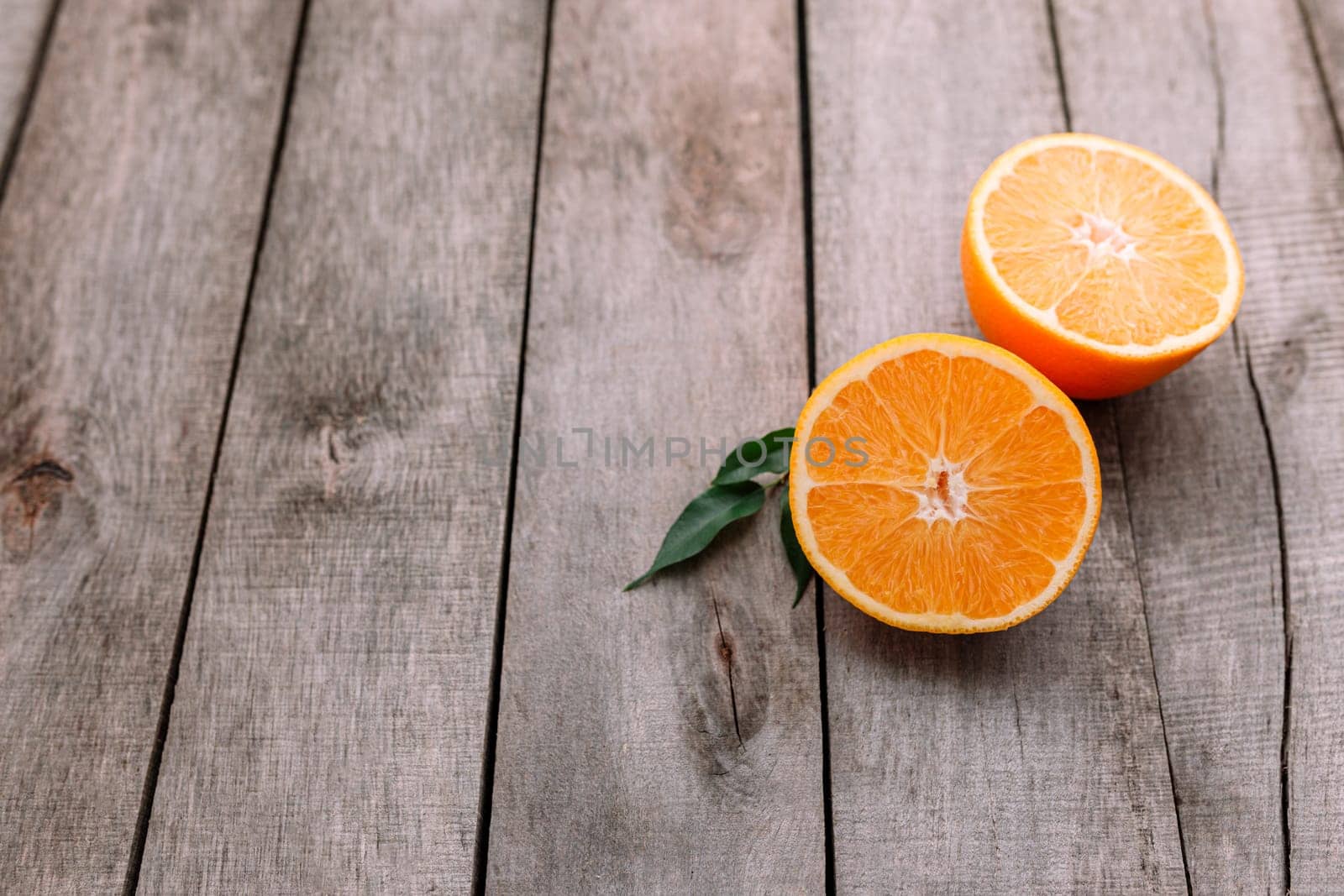 Flat lay with fresh ripe sliced halves of orange fruit on gray wooden background. Orange pulp and green leaves. Tropic food concept. Healthy eating concept. High quality photo