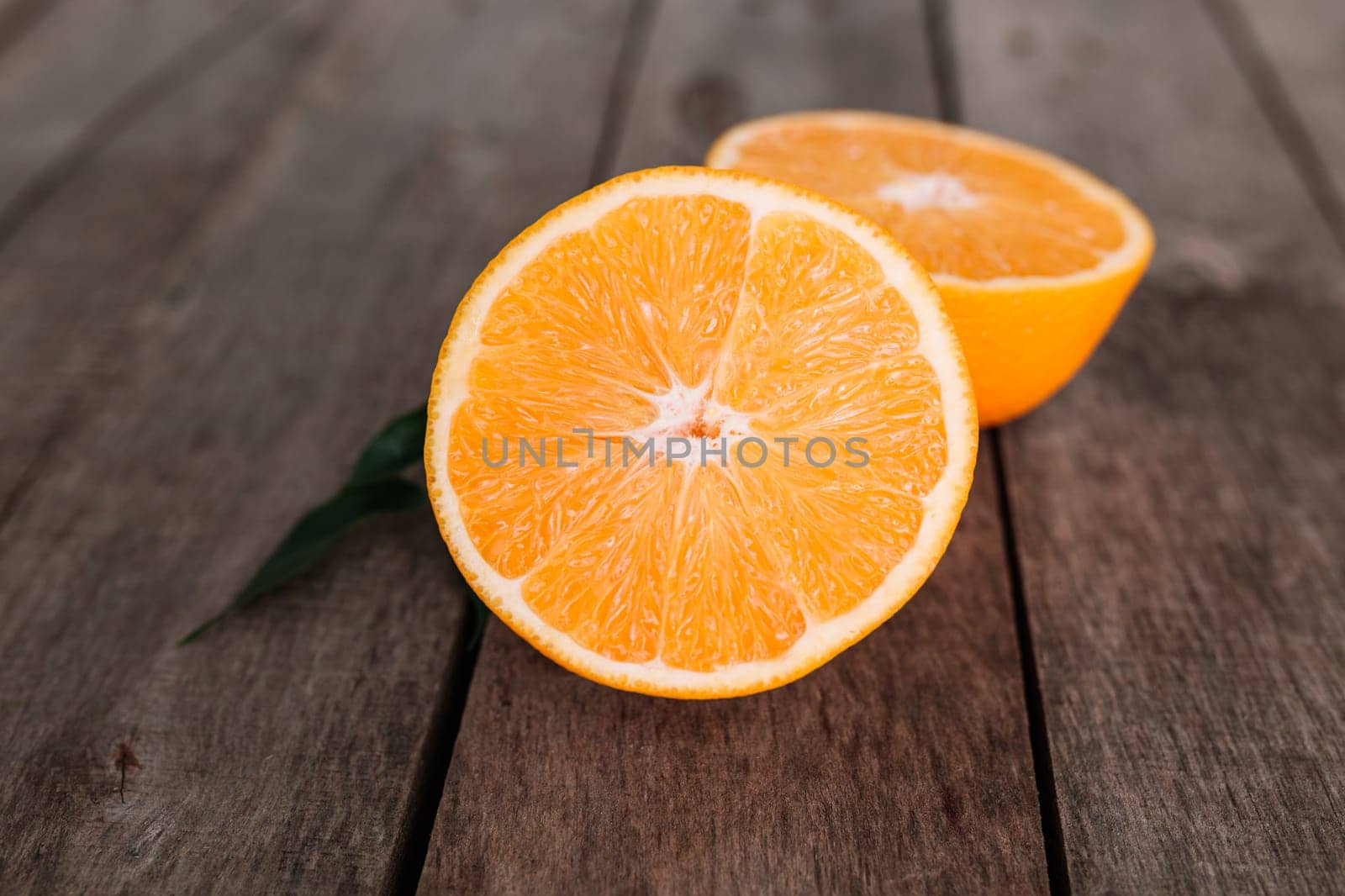 Flat lay with fresh ripe sliced halves of orange fruit on gray wooden background. Orange pulp and green leaves. Tropic food concept. Healthy eating concept. High quality photo
