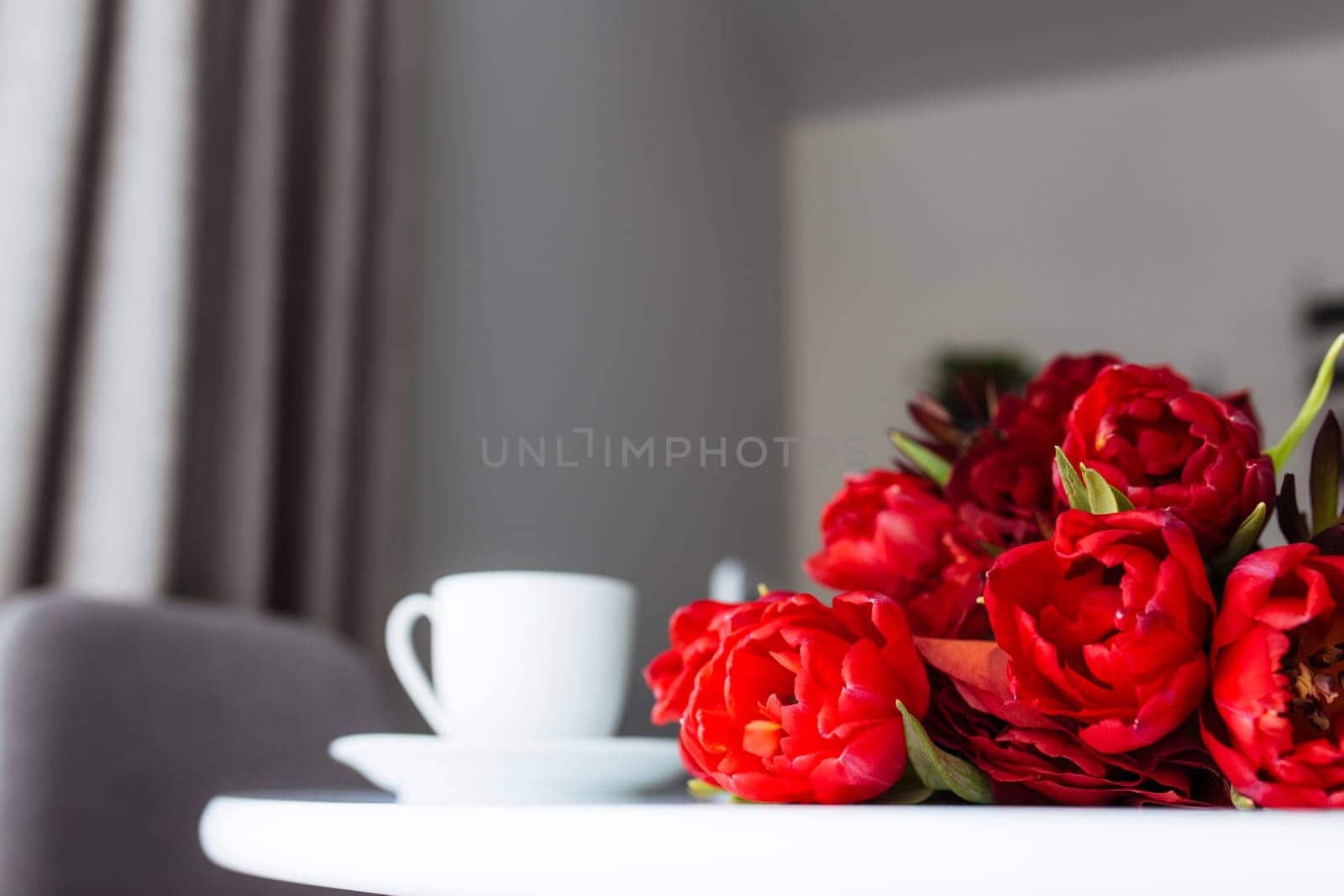 Red tulips bouquete on table, white coffee cup. Concept for greeting card for mothers day, international womans day or valentines day concept, birthday greeting concept