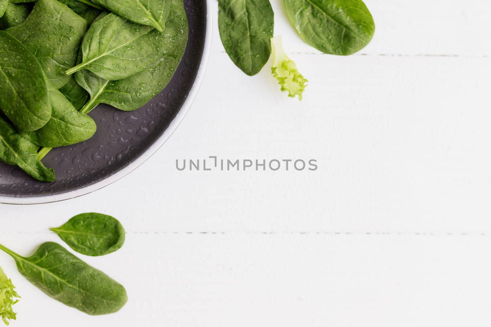 Bowl with fresh green salad leaves, spinach, lettuce, basil on a white background. Healthy vegetarian eating concept. High quality photo