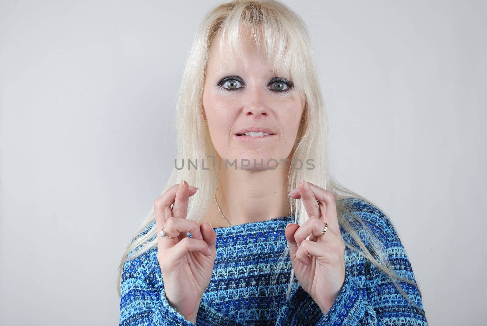 Young blond woman fingers crossed