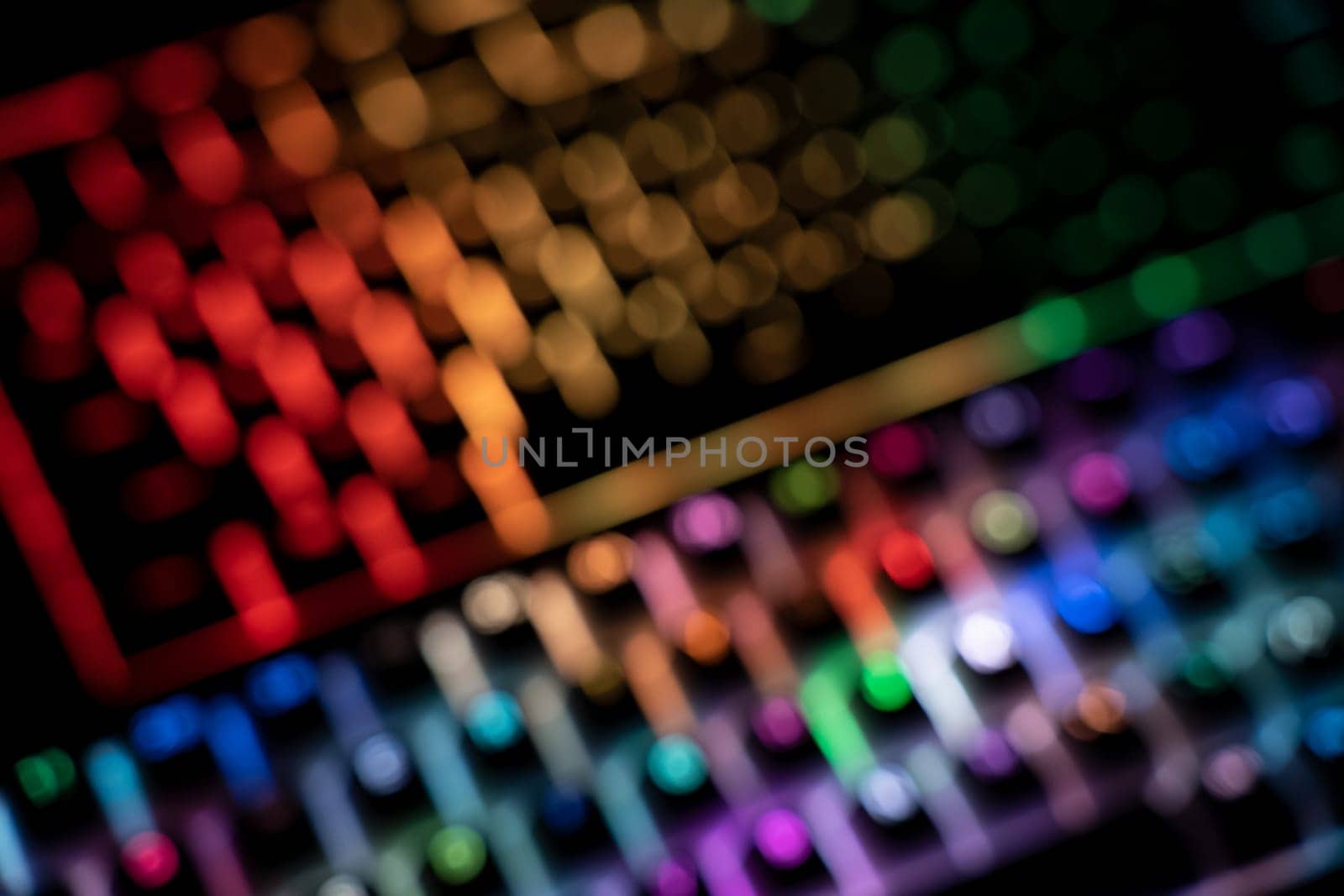 out of focus top view detail closeup of two illuminated mechanical gaming RGB keyboard with keycaps lighting up in different colors in the dark