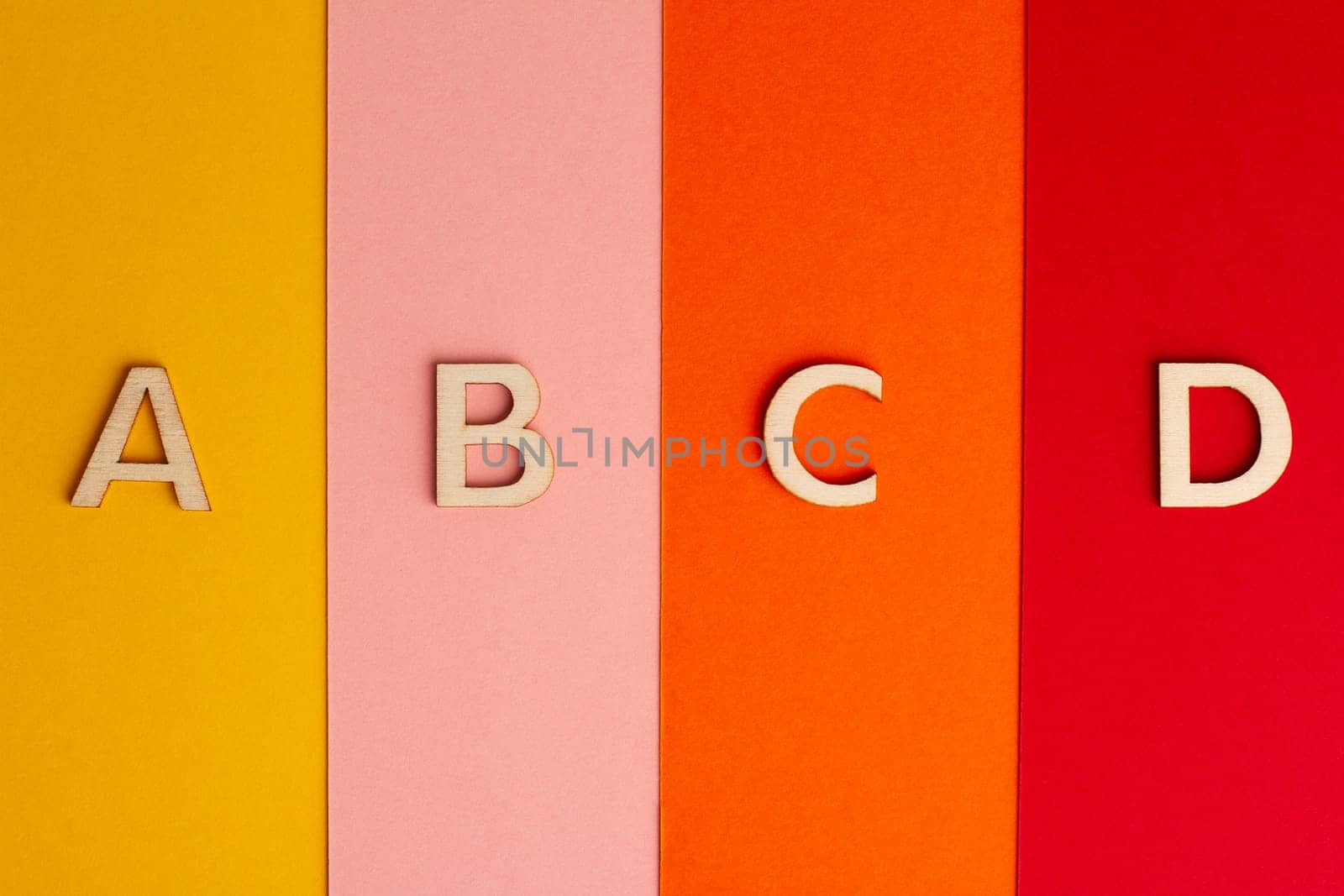 top view perspective closeup of A B C and D letters of the alphabet cut in wood on colored paper background