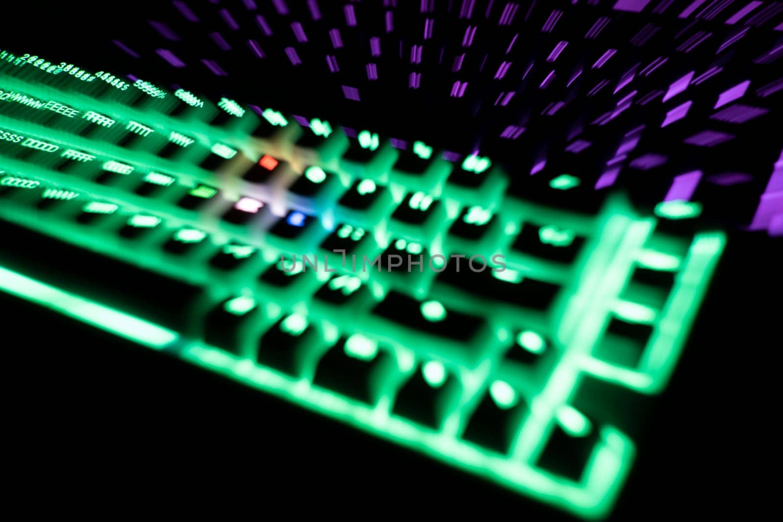 out of focus top view detail closeup of two illuminated mechanical gaming RGB keyboard with keycaps lighting up in different colors in the dark