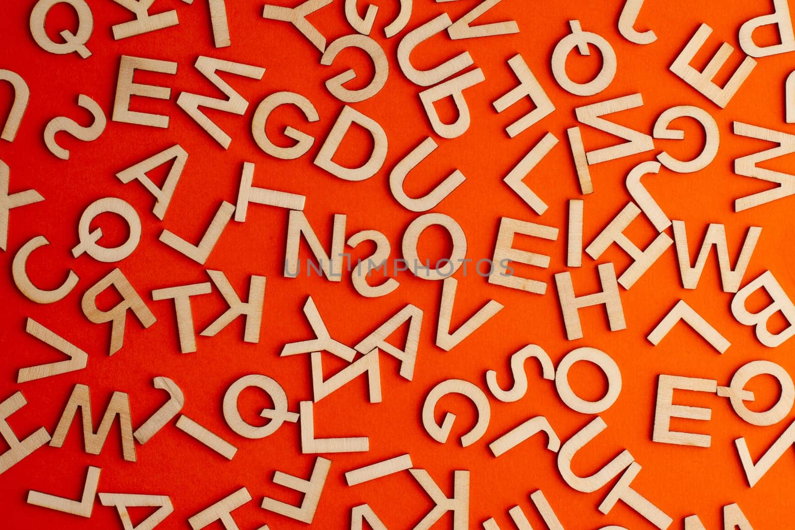 top view closeup detail macro of many wooden cut small alphabet letters on orange background