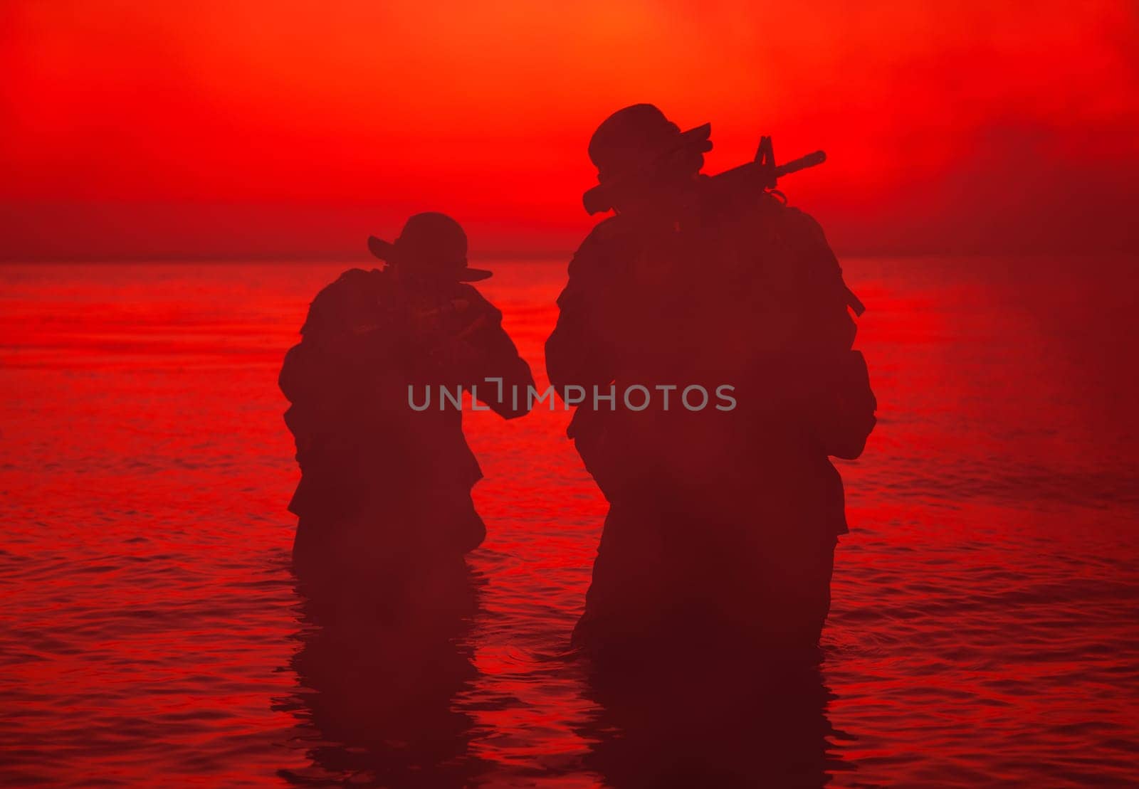 Commando soldiers walking in water, army special operations forces fighters sneaking in darkness, aiming assault rifles and observing shore during amphibious operation on coast at night or dawn