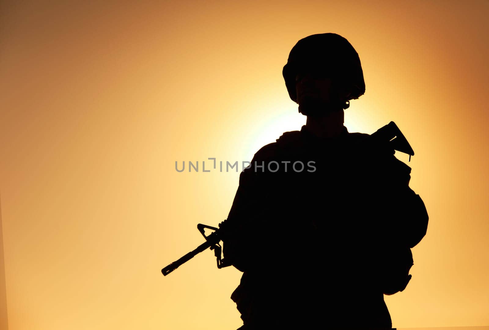 Half-length silhouette of army infantry shooter, special operations forces soldier, Marines rider in combat helmet and ammunition, armed with service rifle standing on background of sunset sky