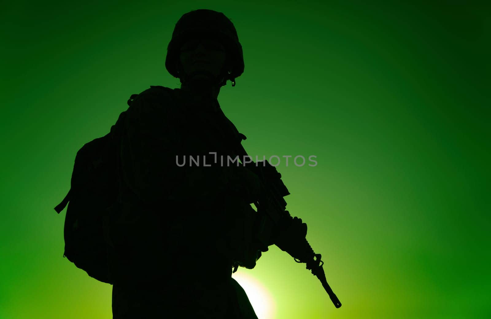 Silhouette of army rifleman in helmet and ammunition, carrying tactical backpack, walking with service rifle on background of sunset sky. Counter terrorist forces fighter marching at night mission