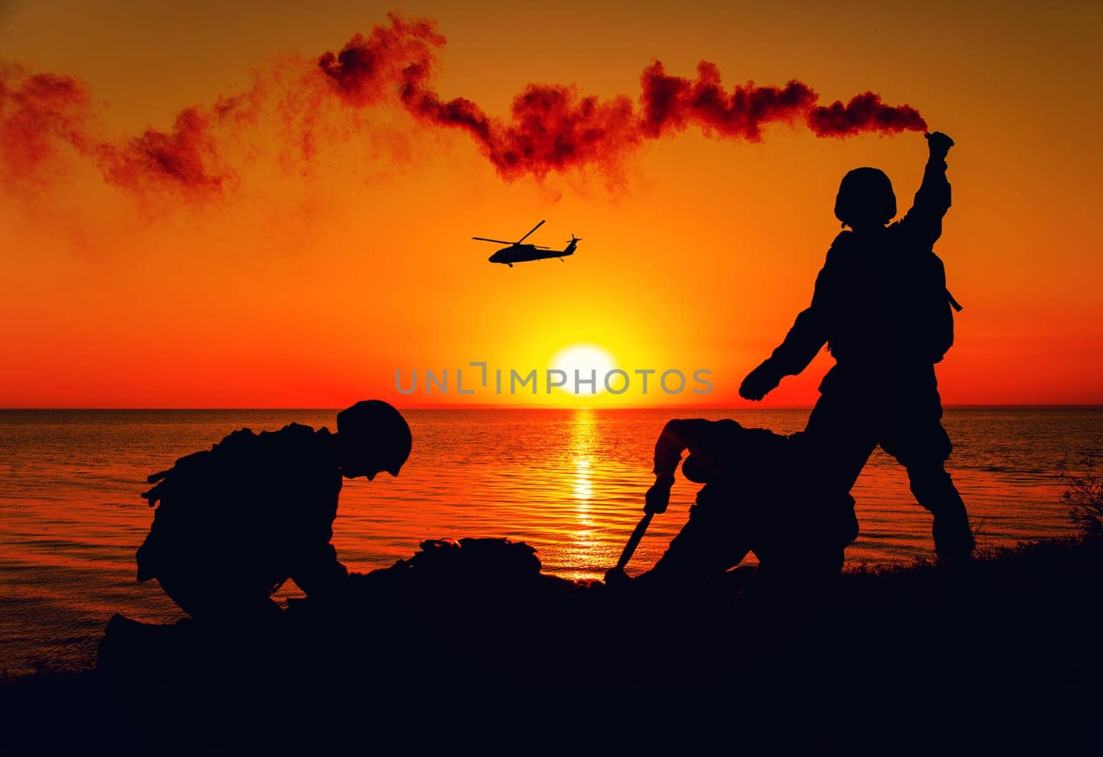 Silhouette of army special forces infantry soldiers, Marines or Navy SEALS team signaling to helicopter with smoke flair while waiting for evacuation, landing on seashore during amphibious operation