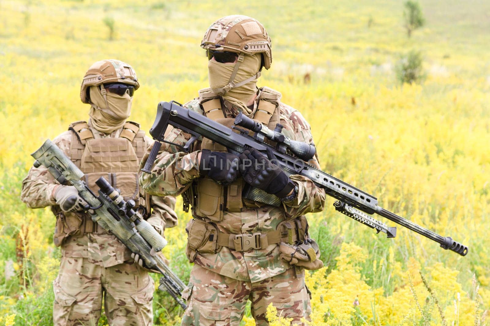 Two equipped and armed soldiers with rifles in the blooming field, team snipers member of ranger squad