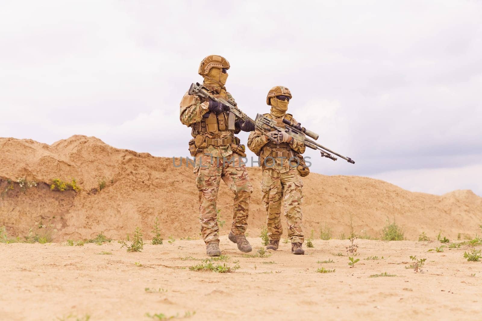 Two soldiers with rifles during army operation in the desert