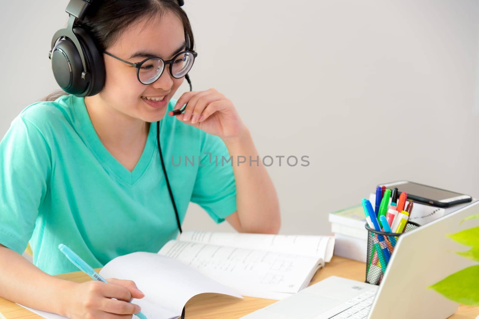 Asian woman looking to talk video conference calling on a laptop computer girl students speak respond with headset microphone class university learning internet online distance education from home