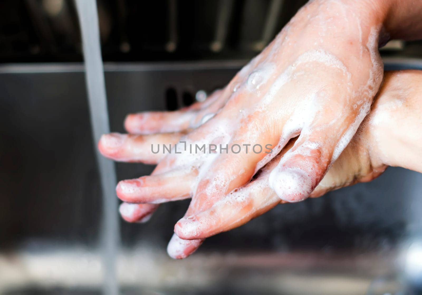 young caucasian woman washing her hands with soap. Right hand over of the left hand. Keeping hands clean. Personal care