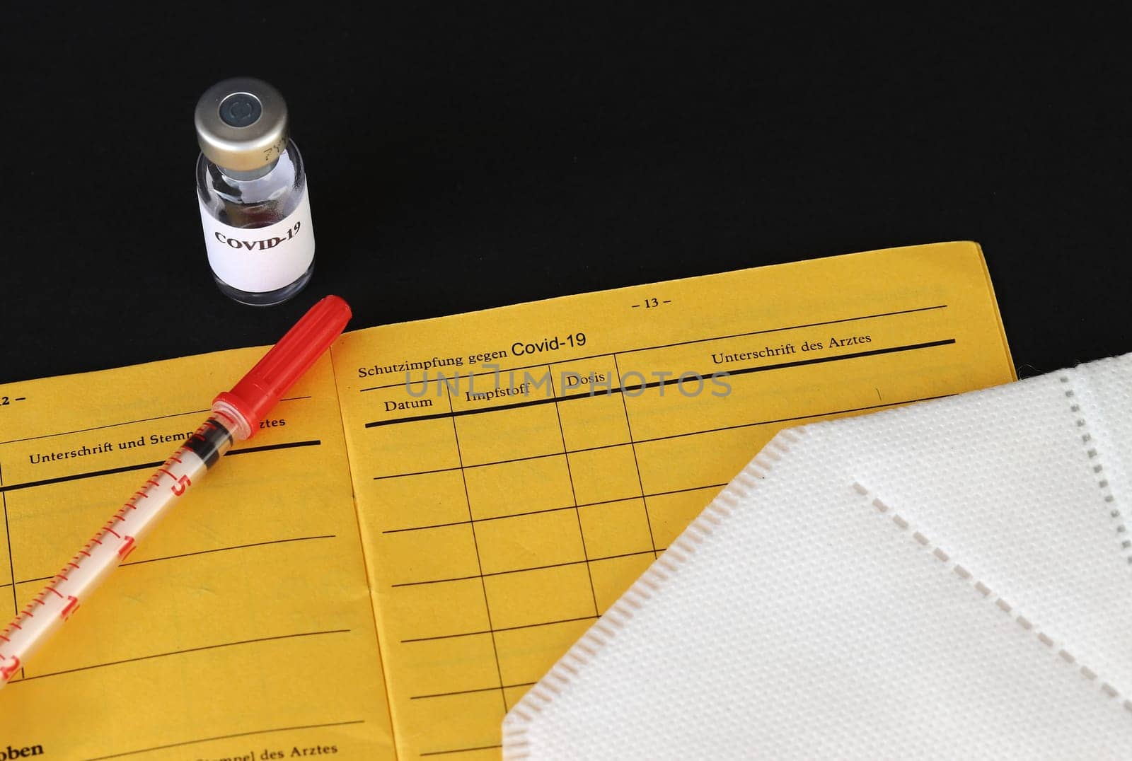 One vaccination against Covid-19. Vaccination certificate, vaccination bottle, syringe and FFP2 mask.