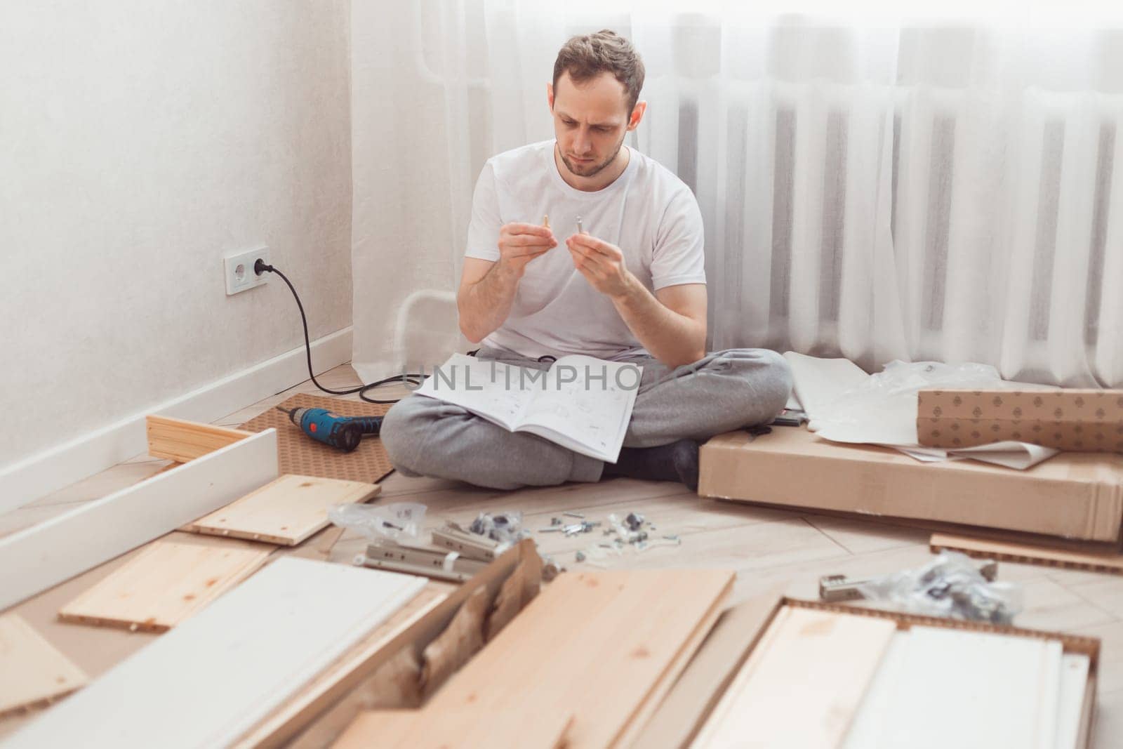Man self-assemblies wooden furniture at home without master. Read instructions. Diy concept.