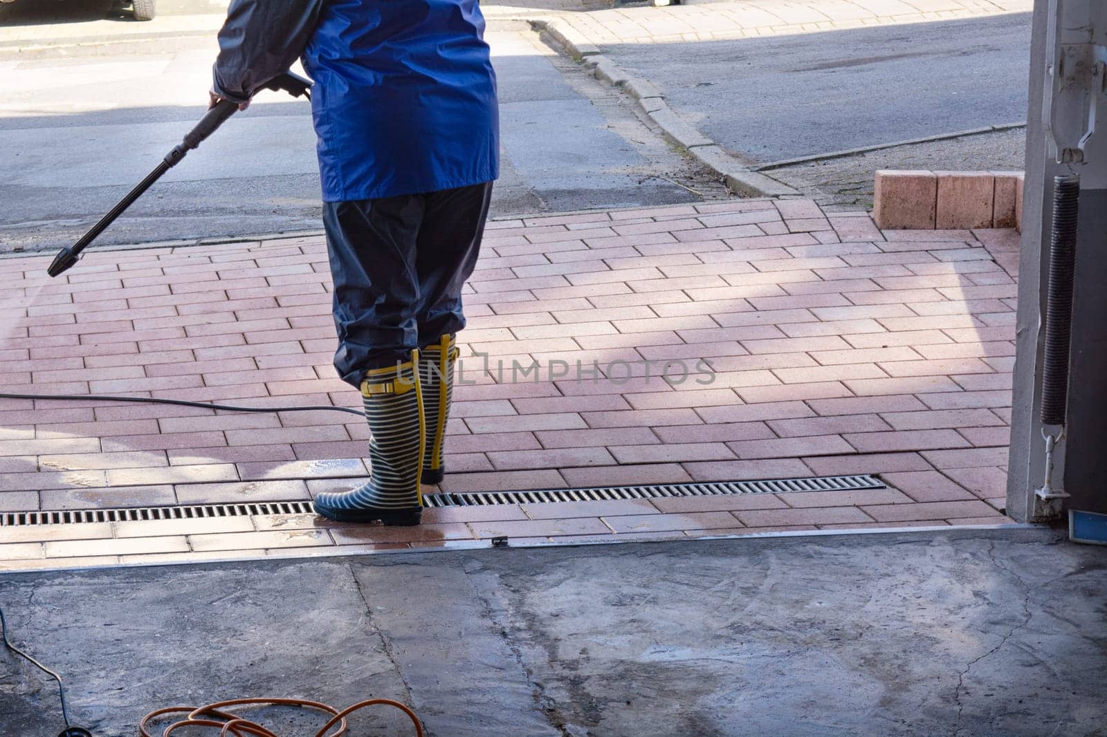 Patio Pressure Cleaning. Caucasian Woman Washing His Concrete Floor Patio Using High Pressured Water Cleaner.