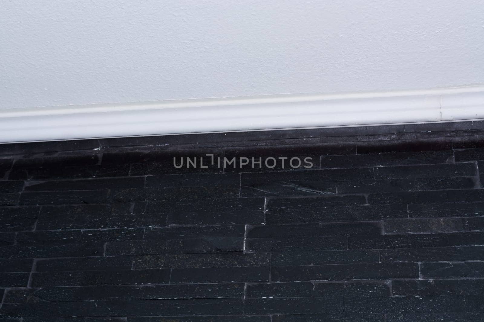Wall with black bricks or straps tiles.