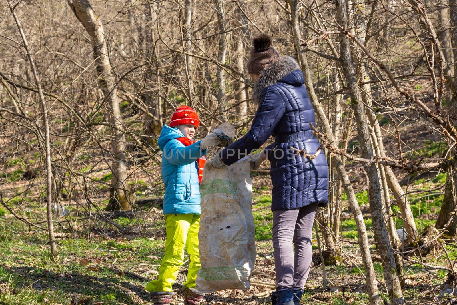A girl collects garbage in the forest, a girl holds a large garbage bag