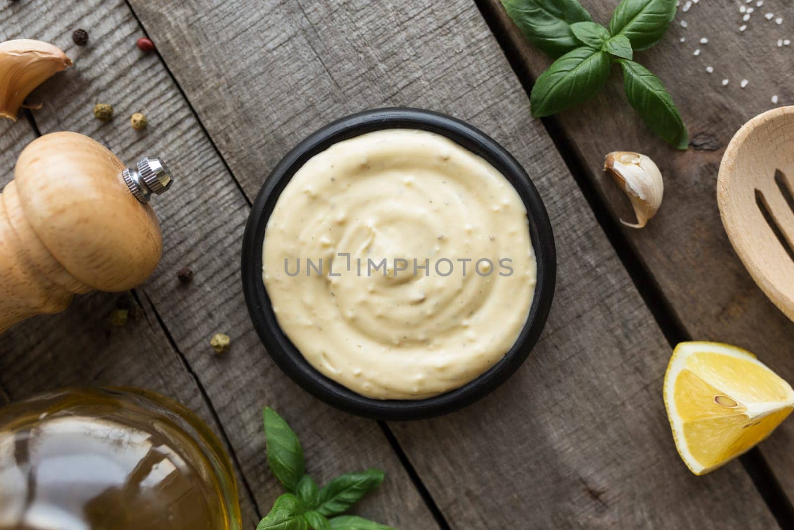 Conceptual flat lay. Making garlic cream sauce or cooking cheese sauce, food and seasoning, homemade mayonnaise, olive oil in glass bottle on wooden background. High quality photo