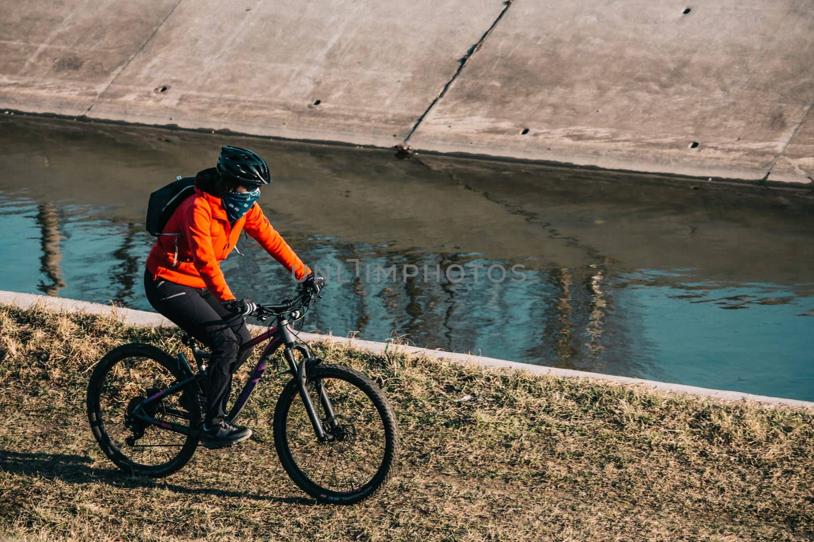 Woman riding a bike next to a river during a sunny day