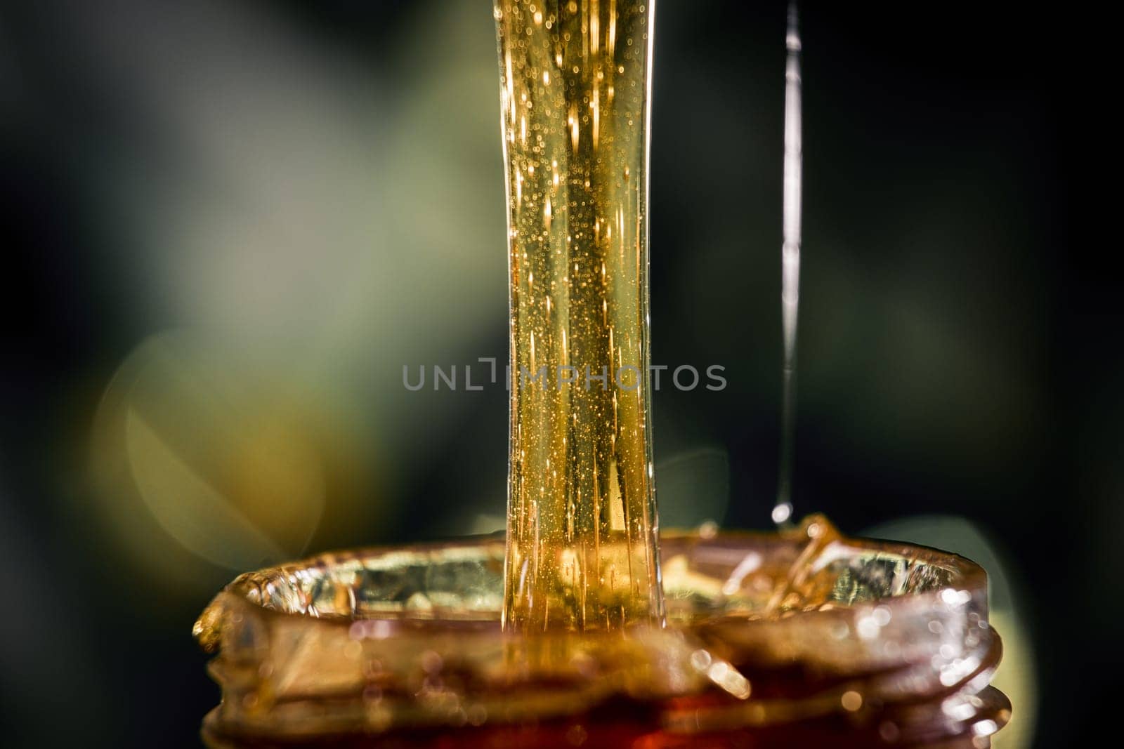 Honey dripping from a wooden honey dipper   on black background