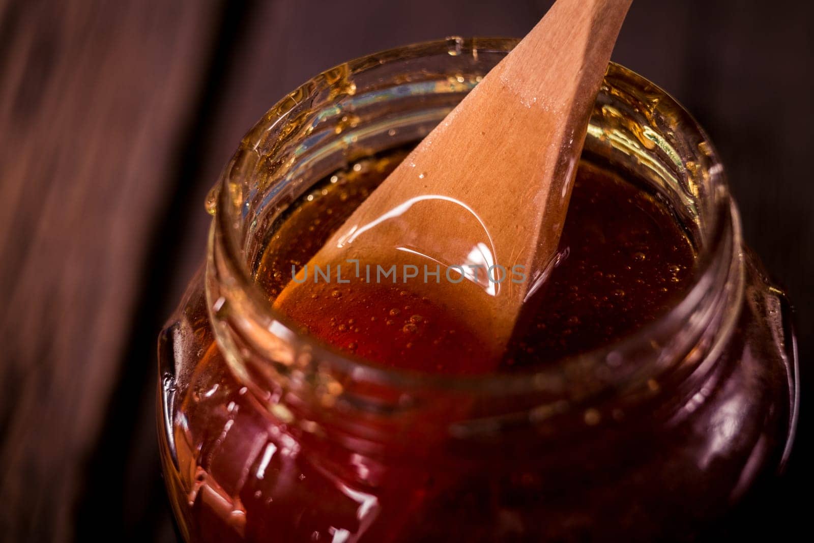 Honey dripping from a wooden honey dipper   on black background