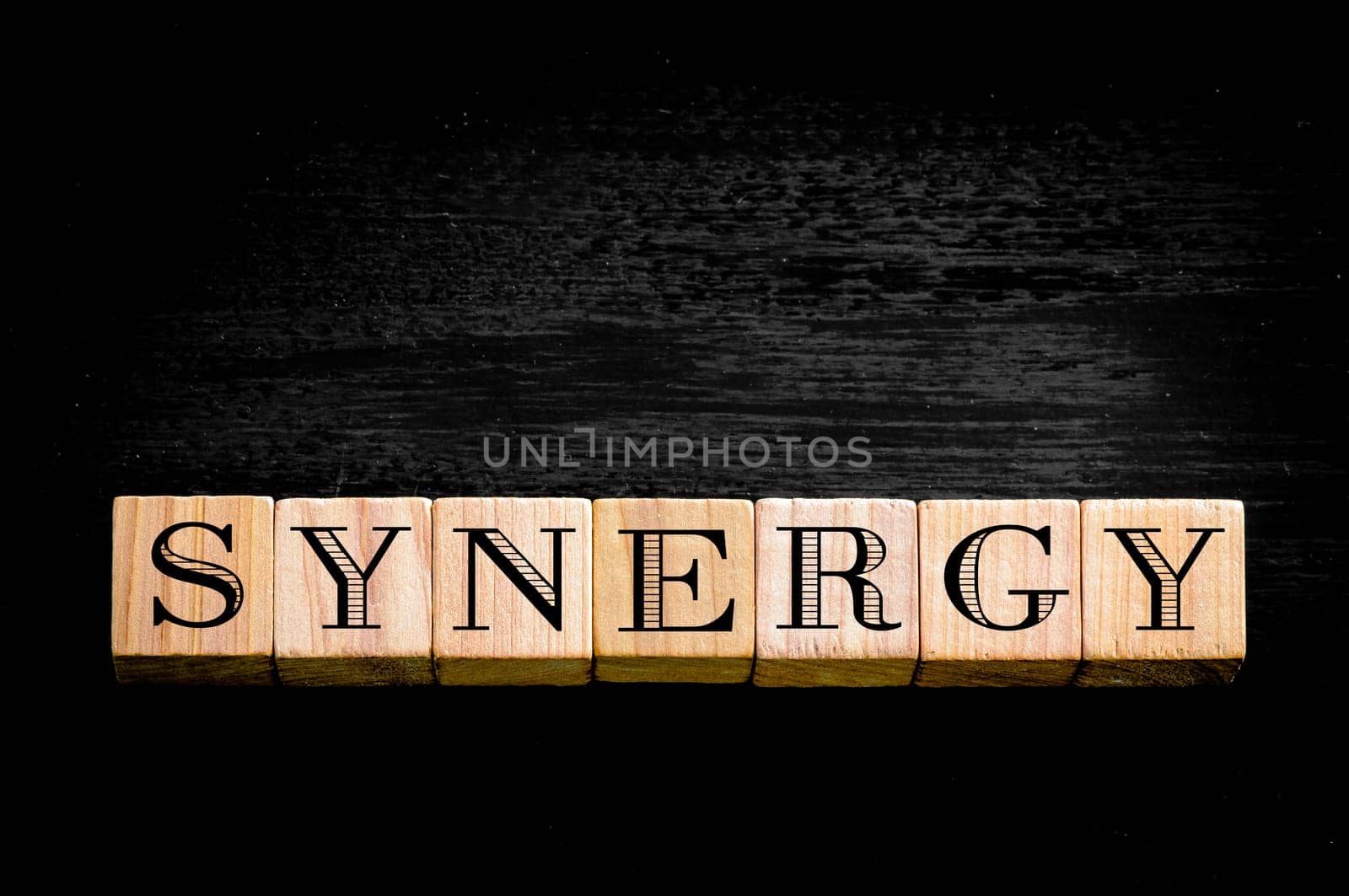 Word Synergy. Wooden small cubes with letters isolated on black background.Concept image.