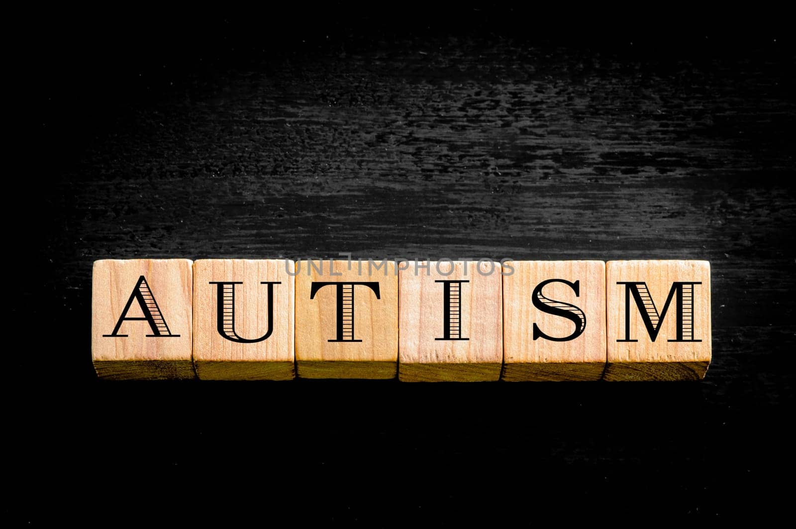 Word Autism. Wooden small cubes with letters isolated on black background.Concept image.