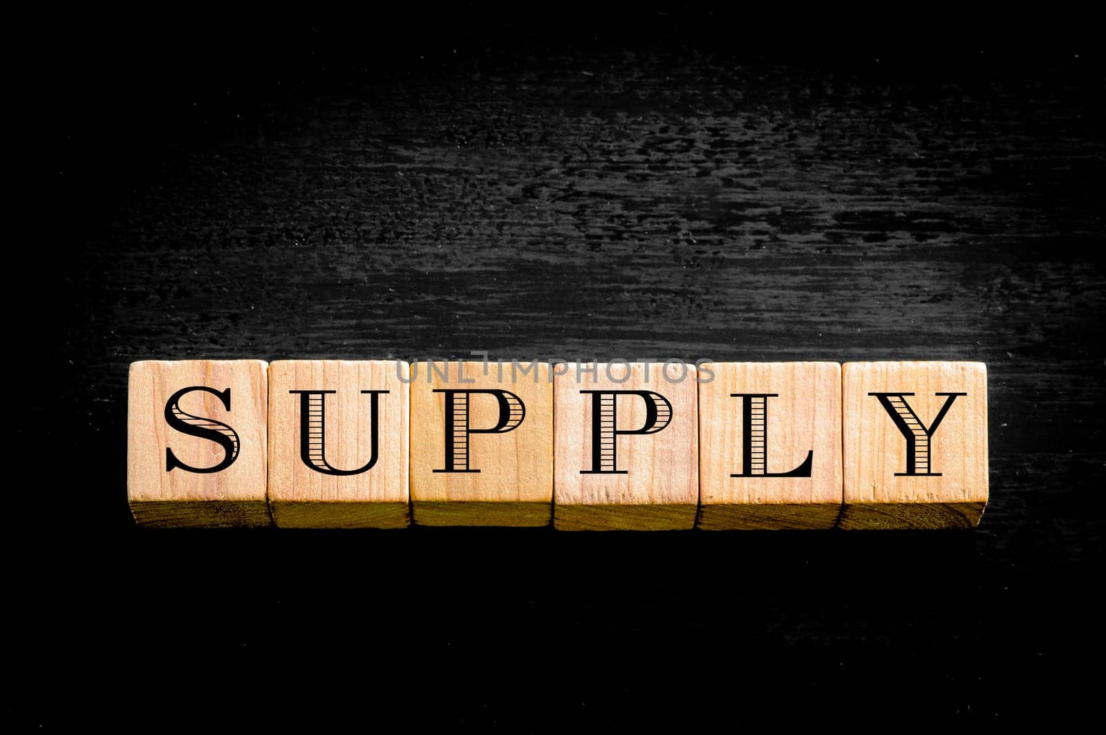 Word Supply. Wooden small cubes with letters isolated on black background.Concept image.