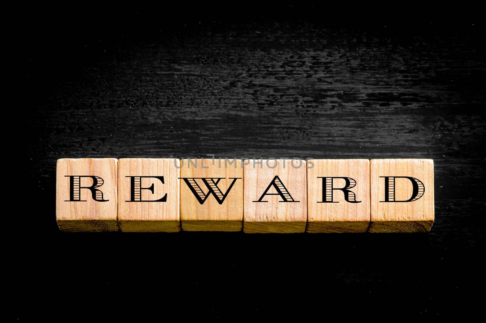 Word Reward. Wooden small cubes with letters isolated on black background.Concept image.