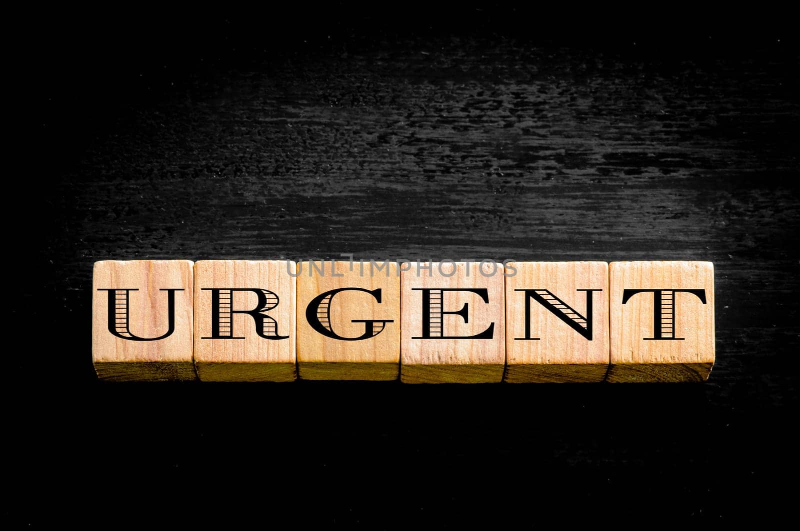 Word urgent. Wooden small cubes with letters isolated on black background.Concept image.