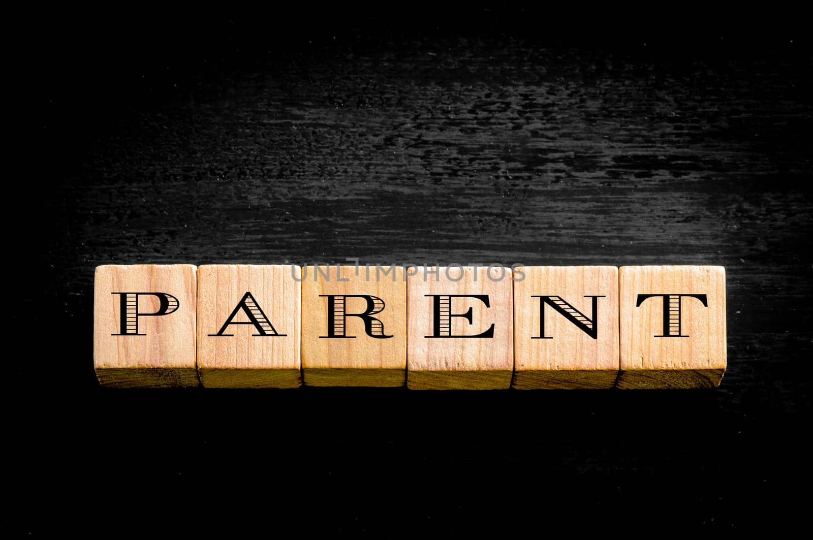 Word Parent. Wooden small cubes with letters isolated on black background.Concept image.
