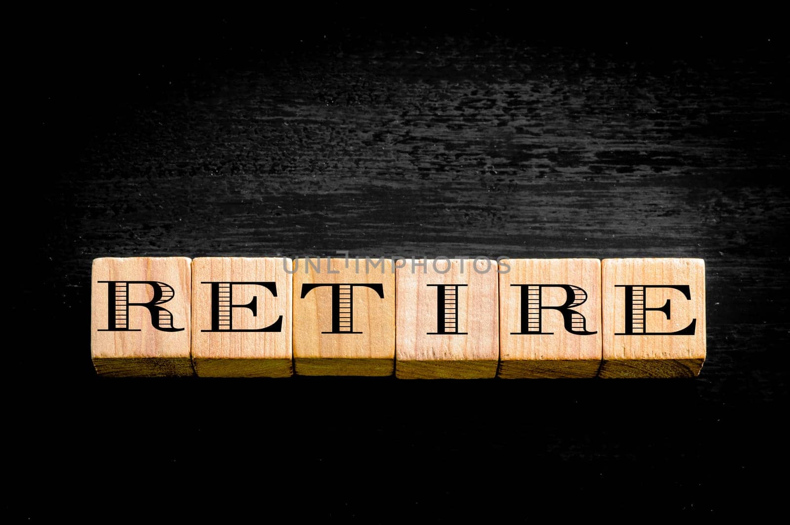 Word Retire. Wooden small cubes with letters isolated on black background.Concept image.
