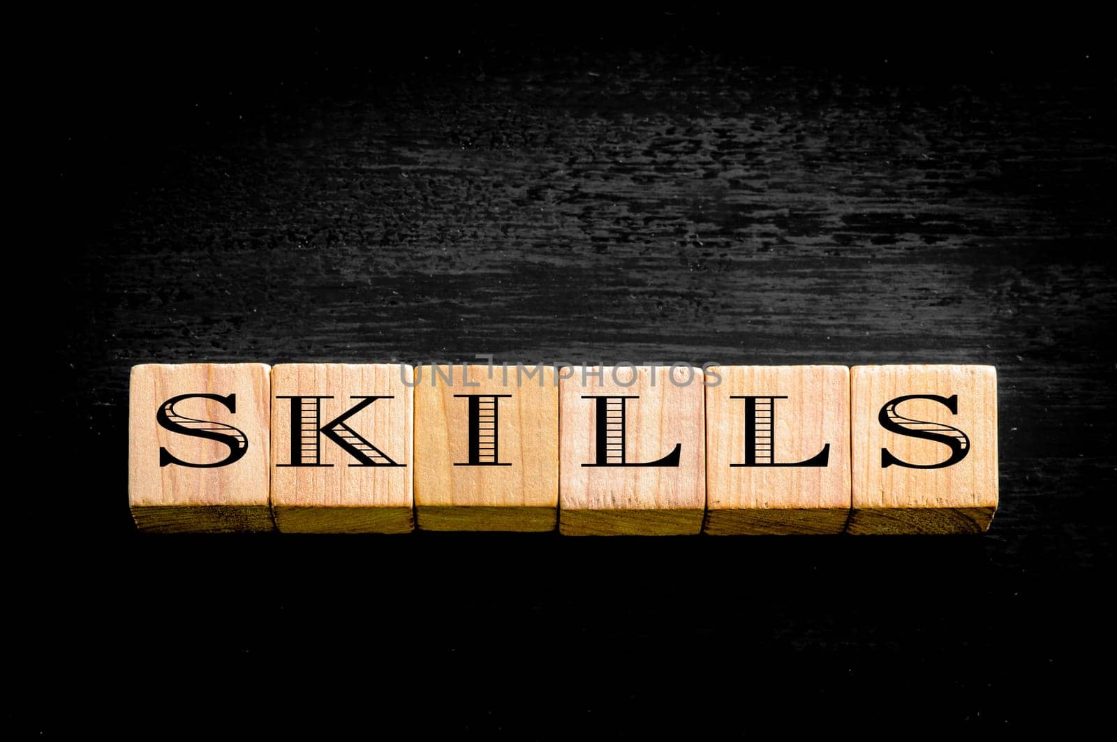 Word Skills. Wooden small cubes with letters isolated on black background.Concept image.