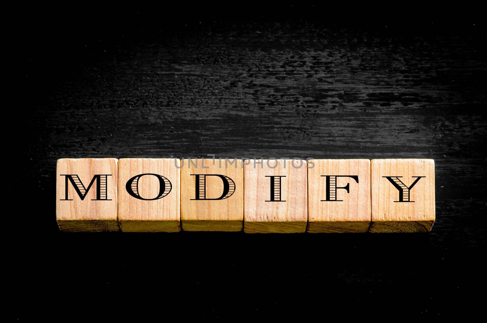 Word Modify. Wooden small cubes with letters isolated on black background.Concept image.