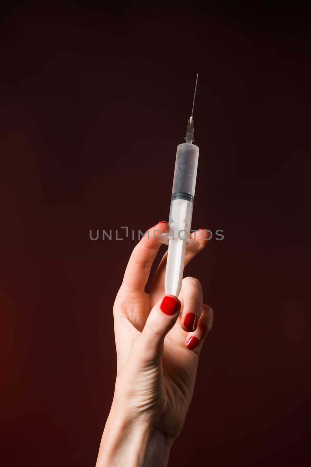A syringe in a hand is isolated on black background