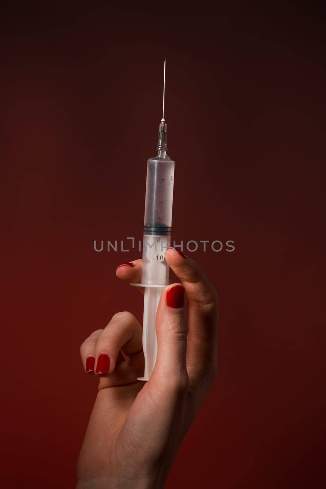 A syringe in a hand is isolated on black background