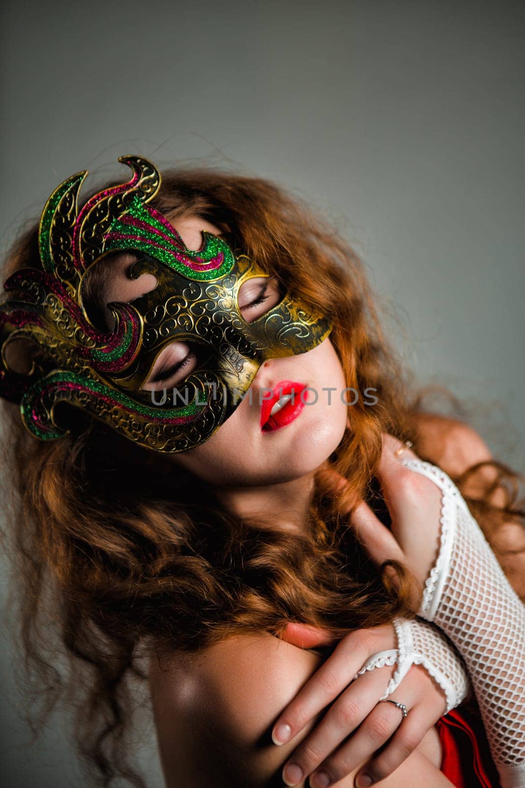 Beautiful Girl in Carnival mask with long curly hair. Masquerade Holidays