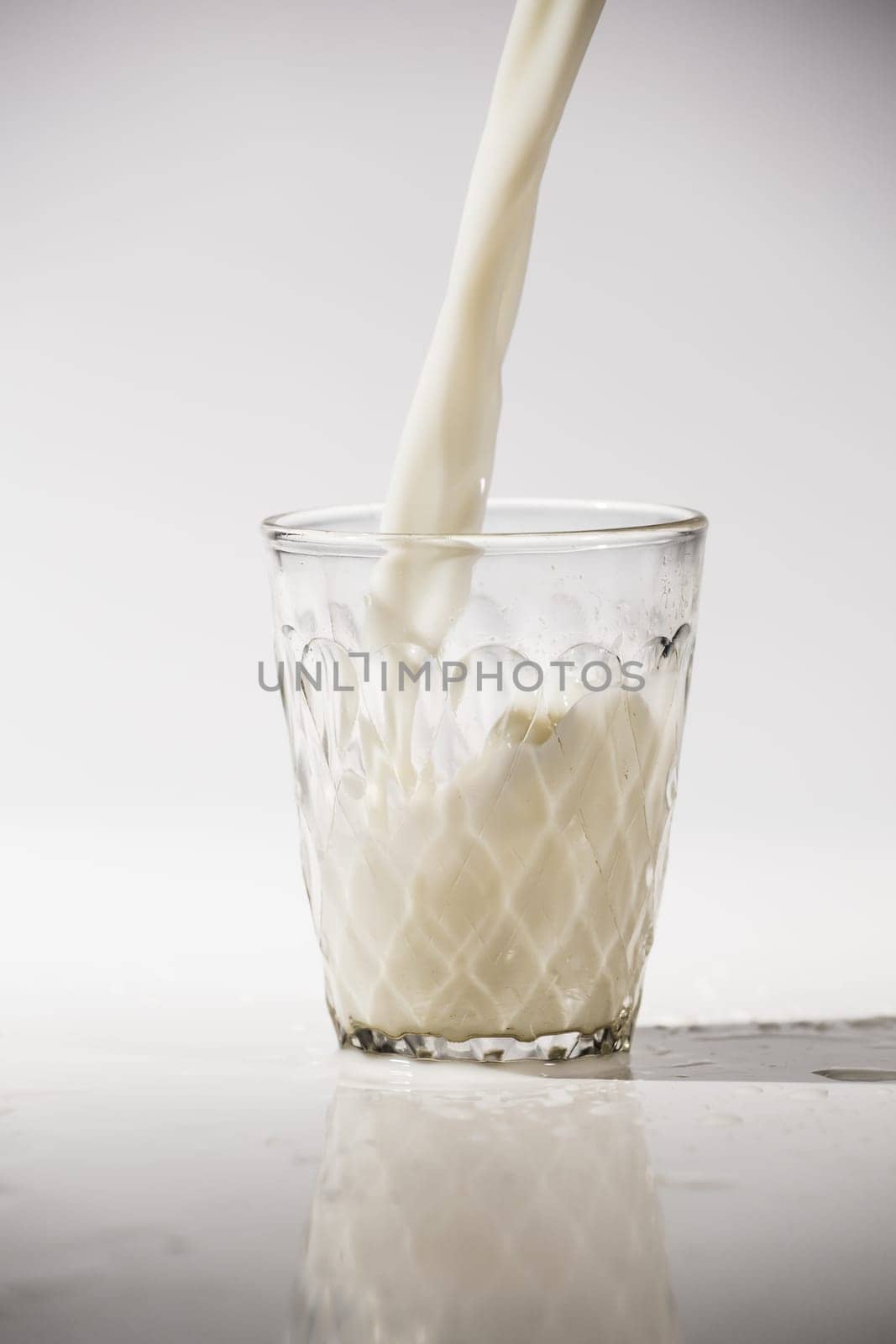 pouring milk in a glass isolated against white background