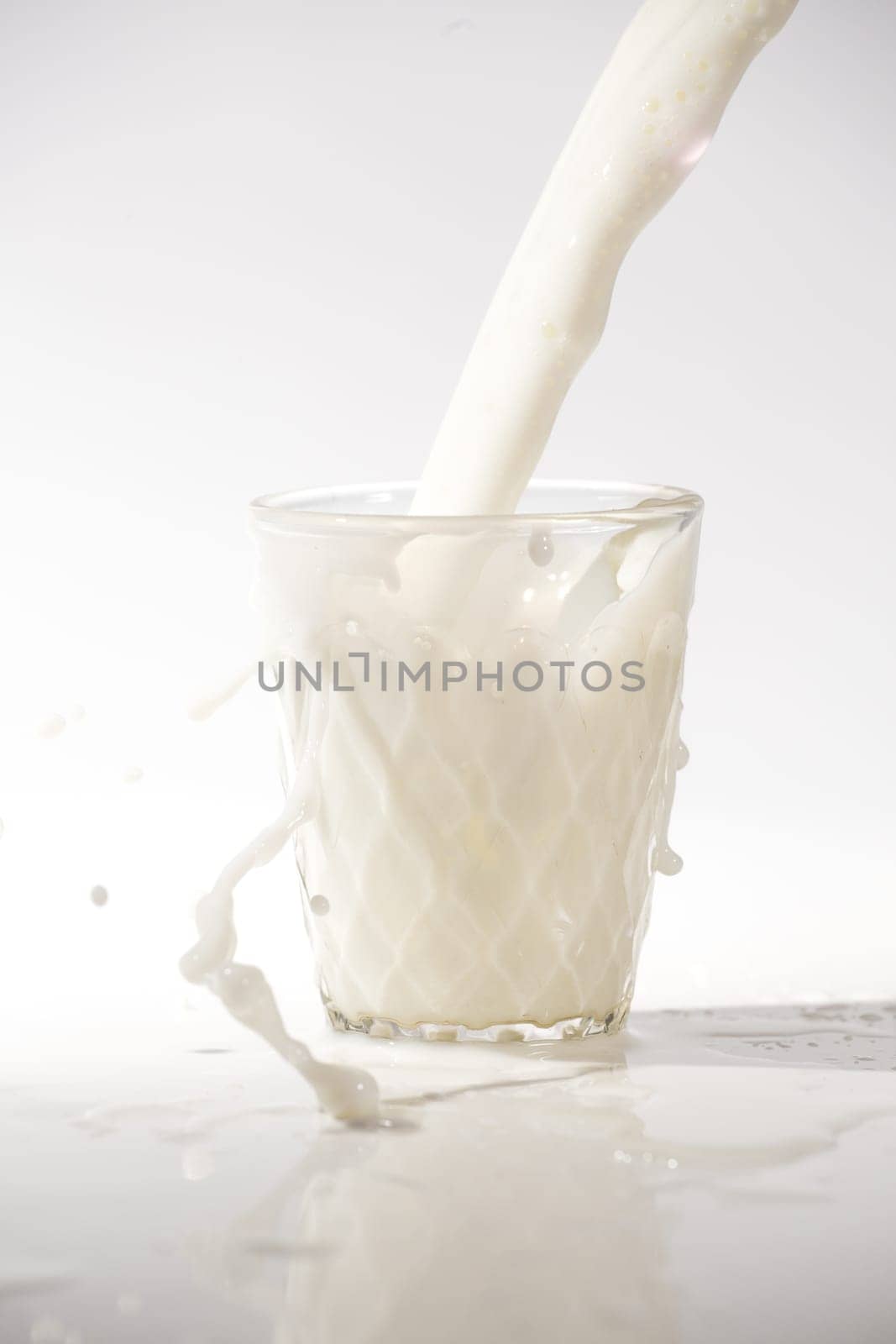 pouring milk in a glass isolated against white background