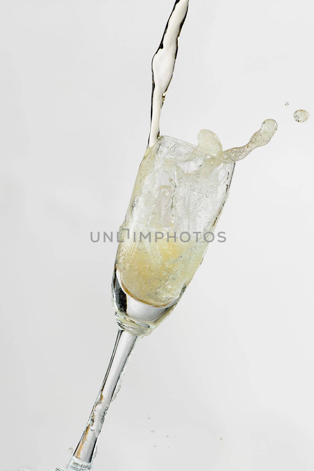White wine splashing out of glass, isolated on white background